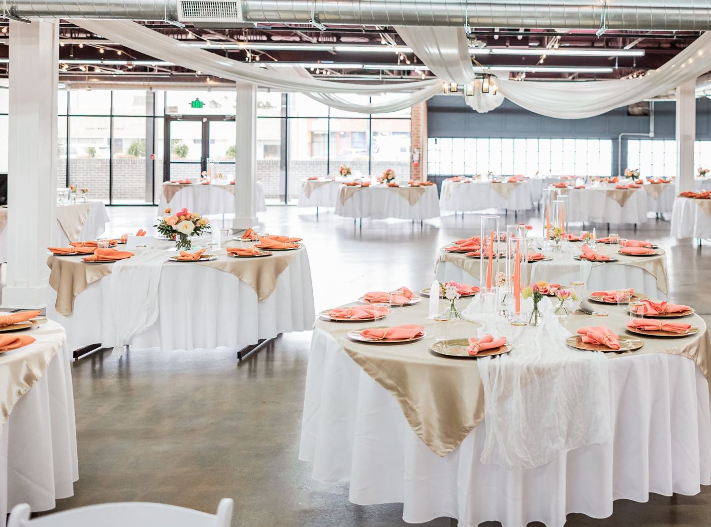 A reception room set with round tables, drapery and a window wall.