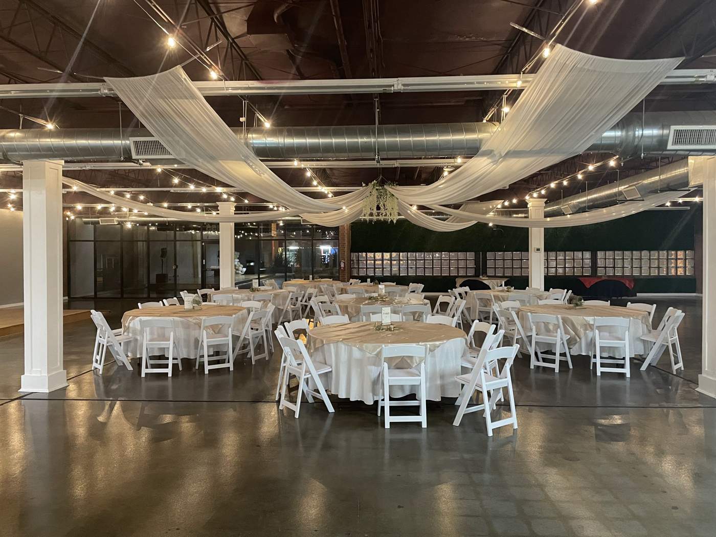 An empty reception room with drapery, white columns and tables set for an evening event.