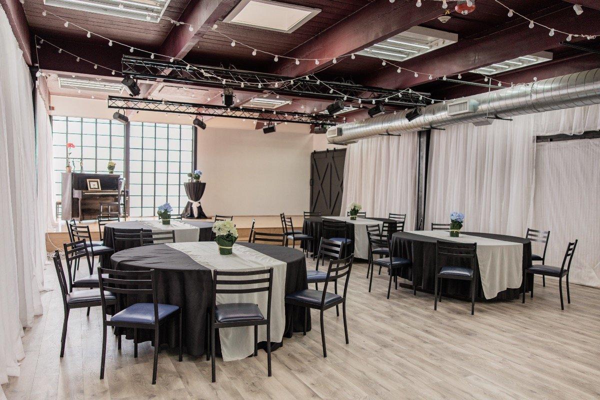 A smaller room with a low stage, piano and barn doors.
